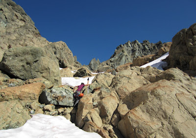 Heading over a rock band in between the small snowfields with the South Ridge in view