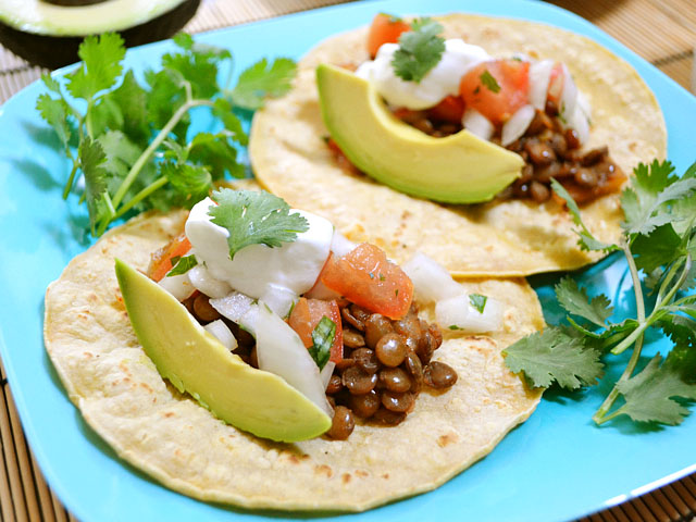 Plate with two lentil tacos and fresh cilantro on the side 