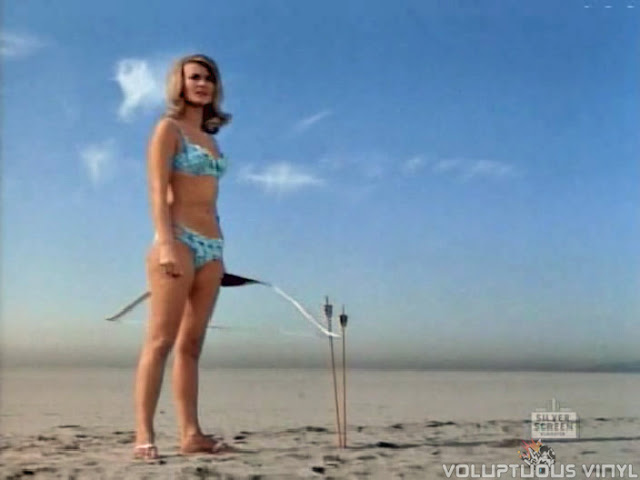 Barbara Bouchet as Ava Vestok with bikini and bow and arrow.