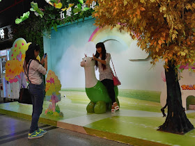 young woman being photographed with a sculpture of an alpaca-like creature