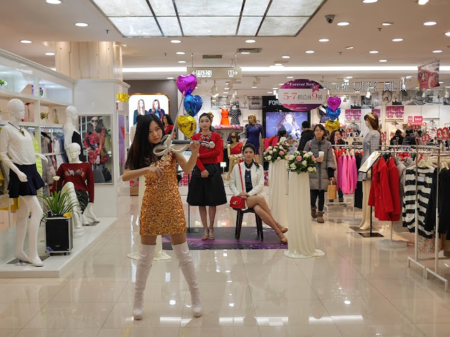 two female models and a female violinist wearing a gold sparkly dress in a Chongqing department store