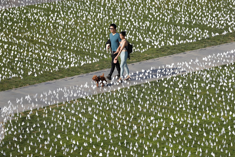 Visitors walk through the Covid-19 memorial "Strength and Love" made of 26,661 white flags on the lawn of the Griffith Observatory in Los Angeles, California, US, November 20, 2021.