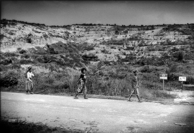 Three Batek women on their way to gather forest herbs pass by signs forbidding entry to land clear-cut two years ago to create an oil palm plantation. Photo: James Whitlow Delano