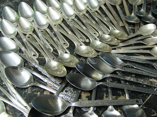 a couple dozen spoons with holes in their handles