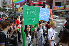 young women hold signs that say free hug and LGBT