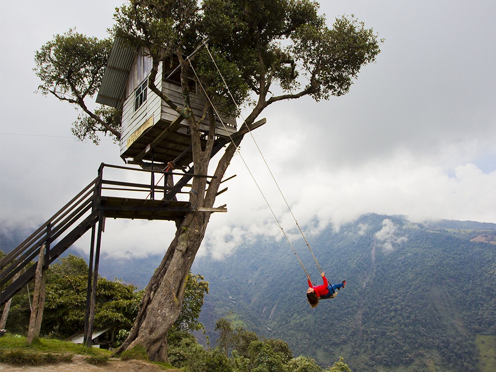 Woman swinging at the famous swing at the "End of the World" located at the La Casa del Árbol (The Treehouse) in Baños, Ecuador. 