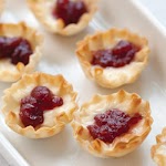 Brie and Cranberry Tartlets Brie and Cranberry Tartlets Makes 45 tartlets 3 (1.9-ounce) packages miniature phyllo pastry shells (45 shells)* 1 cup whole-berry cranberry sauce 1 tablespoon orange zest 1 (8-ounce) wheel of Brie, rind removed Preheat oven to 350°. Line a baking sheet with heavy-duty aluminum foil. Place shells on prepared baking sheet, and bake for 5 minutes. Cool completely on baking sheet. Reduce oven temperature to 300°. In a small bowl, combine cranberry sauce and orange zest. Cut Brie into about 45 pieces. Place 1 Brie piece in each pastry shell; top with about 1 teaspoon cranberry mixture. Bake for 4 to 6 minutes, or just until cheese begins to melt. Serve immediately. *We tested with Athens Mini Fillo Shells. was pinched from <a href="http://www.celebratemag.com/content.aspx?id=15955" target="_blank">www.celebratemag.com.</a>