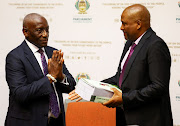 Panel chair Sandile Ngcobo (left) hands the report to parliament secretary Xolile George in Cape Town on November 30 2022. 