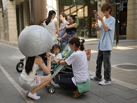 young woman wearing a huge helmet applying lotion to a toddler 