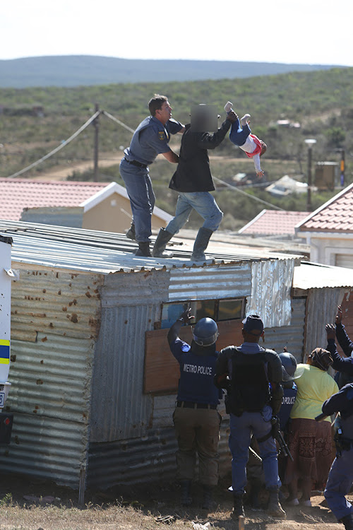 A Port Elizabeth man has been arrested after he flung his child from the roof of his shack while resisting the demolition of the structure.