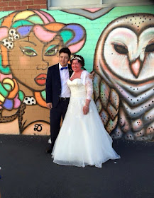 Adam and Carly a Findlay wedding photo - both in wedding attire, in front of street art