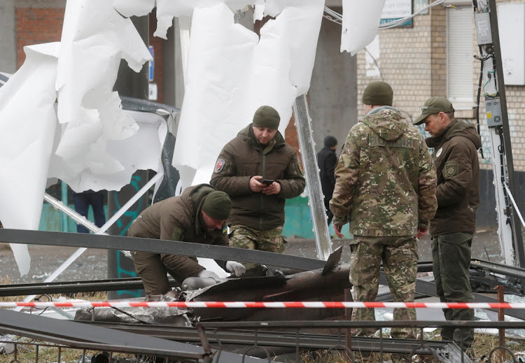 Police officers inspect the remains of a missile that landed in the street in Kyiv after Russia invaded Ukraine.