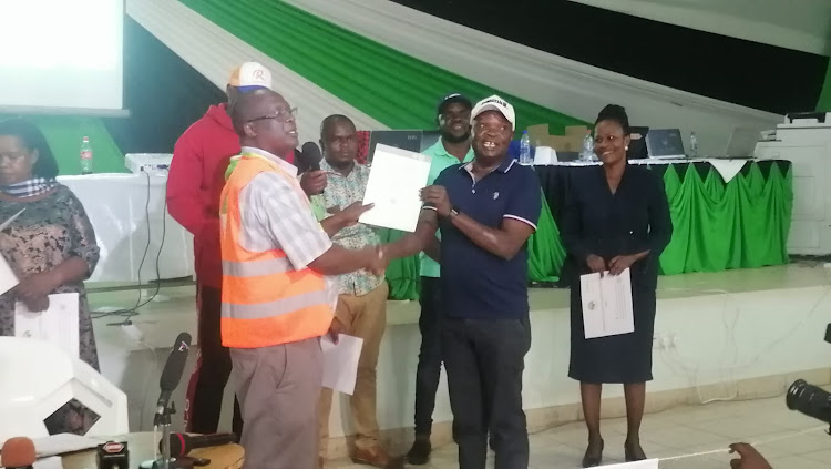 Joshua Oron being handed his certificate by Kisumu central IEBC returning officer.