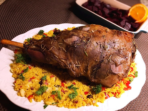 A leg of lamb on a bed of couscous.