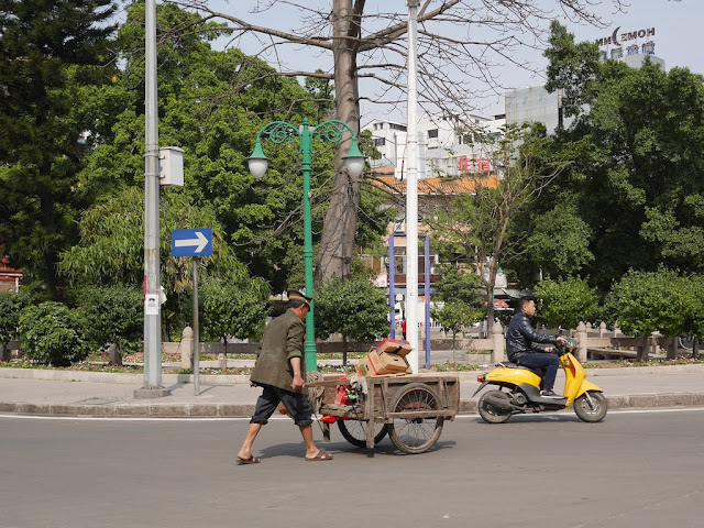 man wearing a police hat pushing a wheelbarrow in Jieyang, China