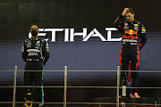 Race winner and 2021 F1 world champion Max Verstappen stands with second-placed Lewis Hamilton on the podium after the Grand Prix of Abu Dhabi at Yas Marina Circuit on December 12 2021 in Abu Dhabi, United Arab Emirates.
