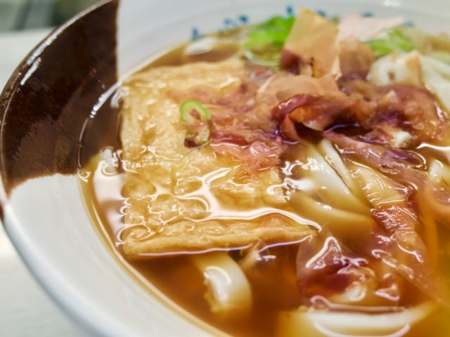 きしめん丼に注がれた黒いスープとお揚げ