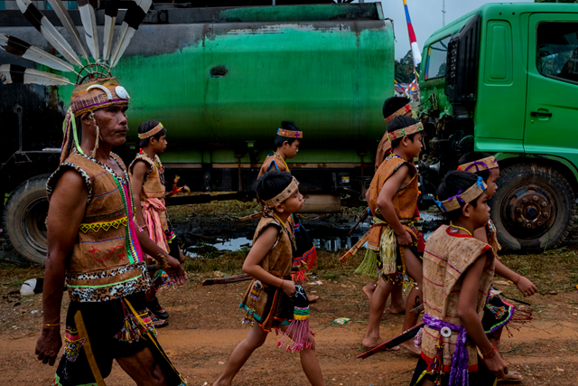 Members of the Wehea Dayak tribe walking past a palm-oil tanker during an initiation ceremony in East Kalimantan, Indonesia. Photo: Ashley Gilbertson / VII Agency / The New York Times