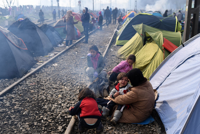 A mother holds her crying child, as her three other daughters sit by the fire outside their makeshift tent in Idomeni, Greece. Photo: Tomislav Georgiev / UNICEF