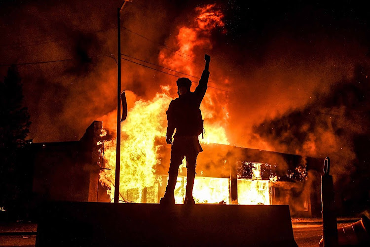 A protester stands in front of a building that was set alight during a demonstration over the death of George Floyd in 2020.