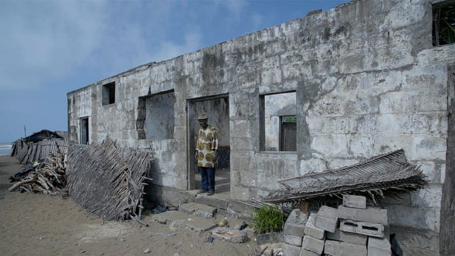 Village chief Diplo Anacle stands in the doorway of an old prison, once one of dozens of stately seafront buildings erected by French colonialists on this sliver of sand between the Atlantic ocean and a giant lagoon. Today, the structure in the centuries-old village of Lahou-Kpanda is all that remains from that time. Photo: Samuel Ouedraogo / Al Jazeera