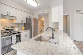 Kitchen with white cabinets and drawers, gray and white stone countertops, and stainless steel appliances 