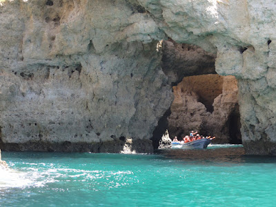 En liten båt med turister sett gjennom en grotte.