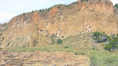 Bandelier National Monument. In the forefront of the photo, the walls of the village of Tyuonyi. Even further back, you can see the walls of the Cliff Dwellings where there are cave rooms we are about to start walking towards. Tree ring dating shows the construction of these homes was more than 600 years ago, and the caves were occupied at the same time. The choice to live in the caves or in the canyon bottom may have been based on family, clan custom, or maybe simply preference