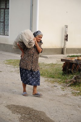 Eine alte Frau trägt einen schweren Sack