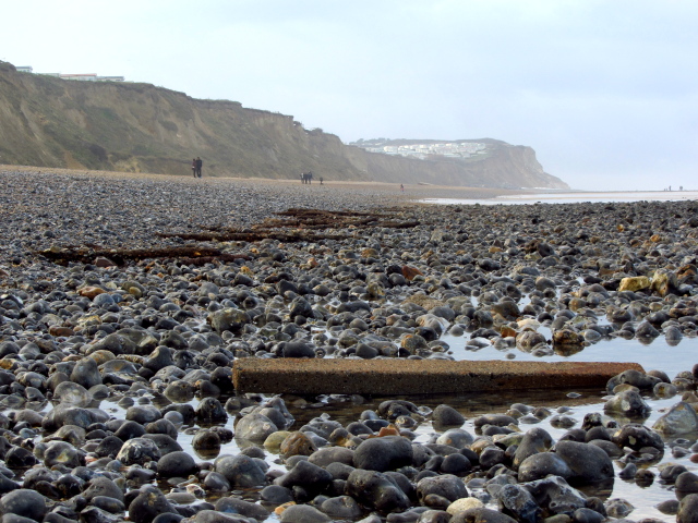 a beach full of rocks and a post of concrete