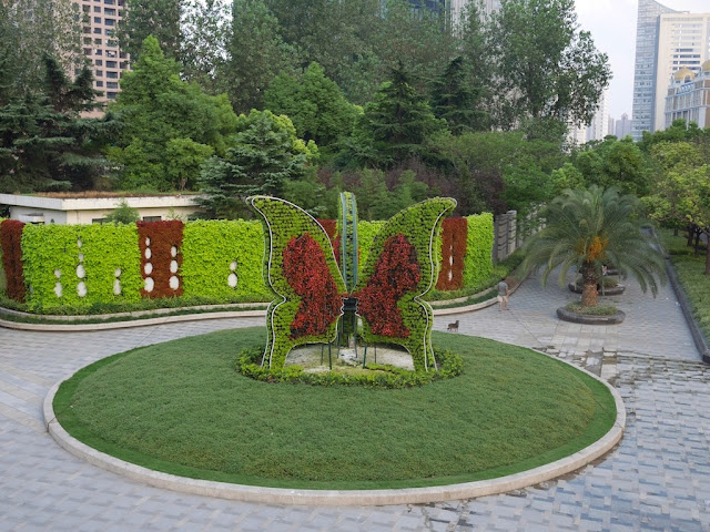 a large butterfly made out of plants standing in a grassy circle