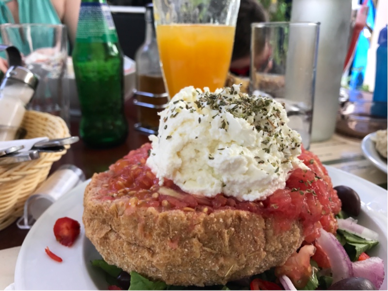 Et tykt stykke brød med hakkede tomater og hvit ost med urter på toppen. Litt salat i bunnen.