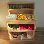 Montessori is all about fostering independence. This beautiful snack hutch presents all the materials our toddlers need to set up their own snack: place mats showing where dishes go, napkins, plates, glasses and, of course, snack food. Notice that there are also clean-up materials to complete the snack cycle!