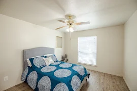 Furnished bedroom with wood-inspired flooring, window with blinds, light walls and trim, and a ceiling fan