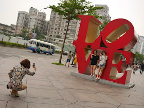 two young women having their photograph taken in front of a sculpture of Robert Indiana's "LOVE" design in Taipei, Taiwan