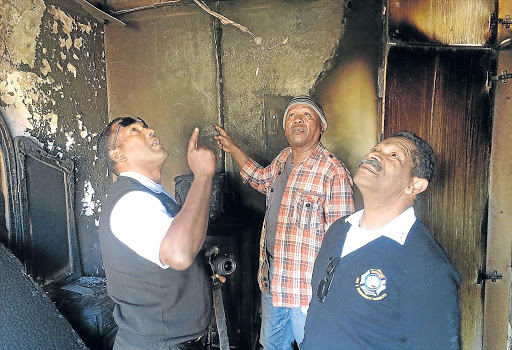 LOOKING FOR CLUES: Anele’s father Leslie Ngcongco, centre, with Buffalo City Metro fire safety inspectors at the scene of the fire yesterday Picture: ZWANGA MUKHUTHU