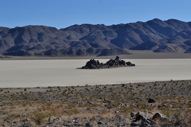 stark black rock rises from light flat