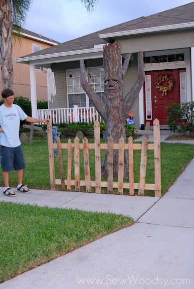 Man holding up a test piece of fence in a front yard. 