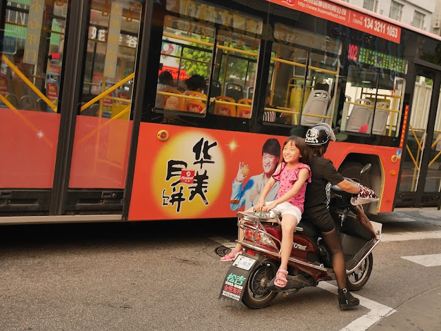 girl facing backwards riding on the back of a scooter
