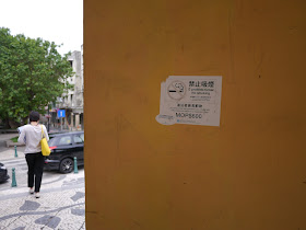 a no smoking sign on an outdoor wall in Macau