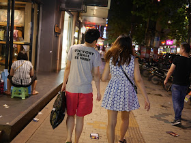 young man wearing a shirt with "VICTORY SHALL BE MINE!" on the back walking with a young woman