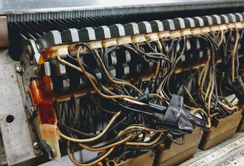 Closeup of the hammer electromagnets in the IBM 1403 printer. An electromagnet (when energized through its pair of wires) pulls a metal armature, which drives the hammer, paper and ribbon against the type slug. There are 132 hammers, one for each column, arranged in two rows of 66.