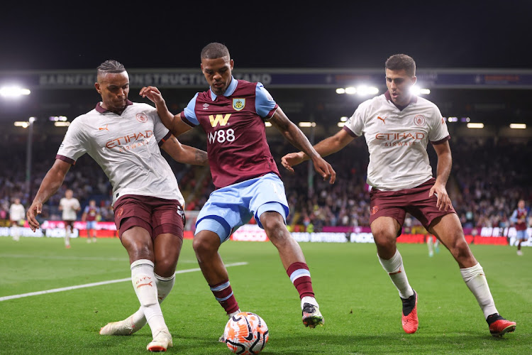 Lyle Foster of Burnley is challenged by Manuel Akanji and Rodri of Manchester City in their Premier League match at Turf Moor in Burnley on August 11 2023.