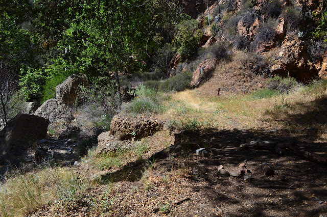 trail dropping into the creek bed on the left, a hole in the cliff on the right