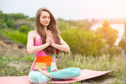 Pretty woman doing yoga exercises on nature landscape