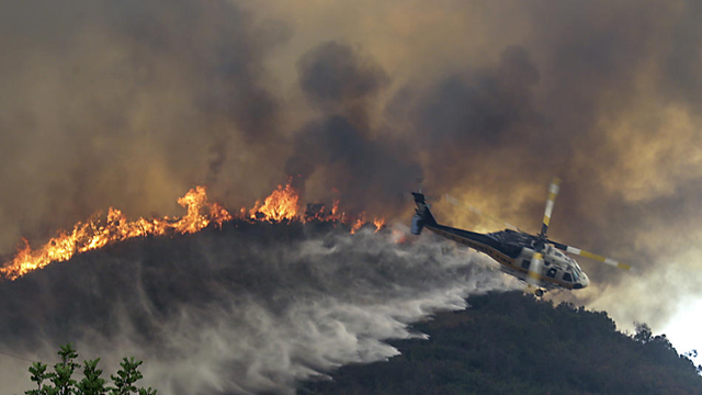 A helicopter drops water as the La Tuna fire approaches homes on Oro Vista in Sunland, 2 September 2017. Photo: Irfan Khan / Los Angeles Times