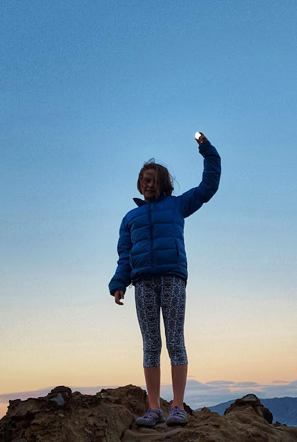 Photo of a girl seemingy holding the moon in her fingertips