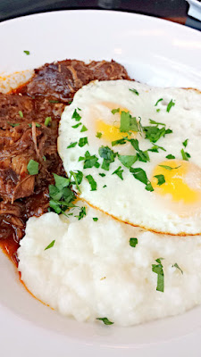 Breakfast at the Country Cat at PDX Airport of The Slow Burn with 2 sunny-side up eggs over slow cooked pork chili & grits