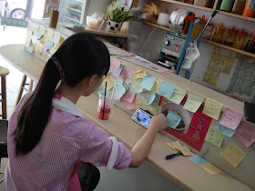 girl viewing Chinese video on a mobile phone and many colored notes with messages on them at the Black Tide (黑潮) cafe