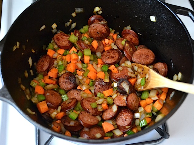 Vegetables added to soup pot with sausage